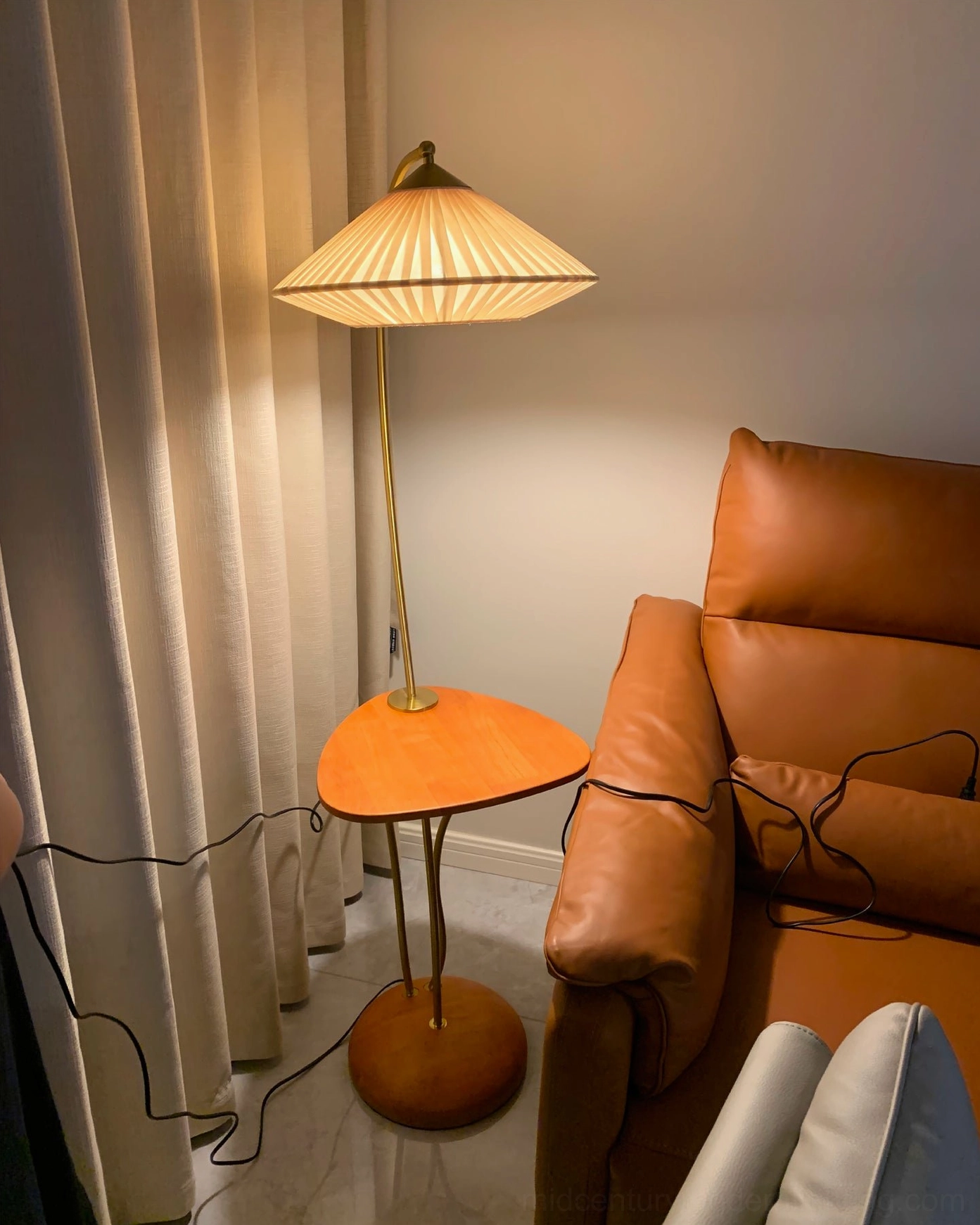 Bertil floor lamp in contemporary interior space, warm brass gold finish and walnut wood base with ambient lighting