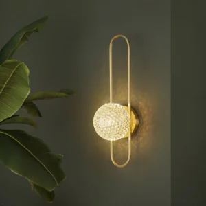 Modern brass wall lamp mounted in contemporary home with dark green accent wall and indoor plants