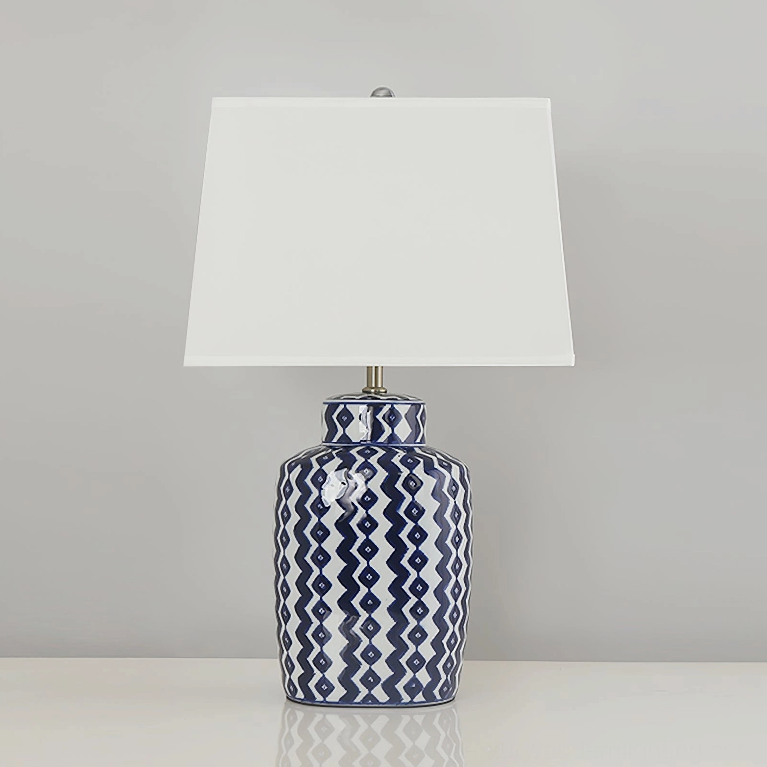 Beryl blue and white ceramic table lamp with white tapered fabric shade in minimalist studio setting