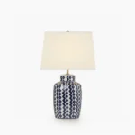 Beryl blue and white ceramic table lamp with geometric chevron pattern, white drum shade, and satin nickel hardware in studio lighting