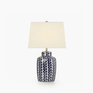 Beryl blue and white ceramic table lamp with geometric chevron pattern, white drum shade, and satin nickel hardware in studio lighting
