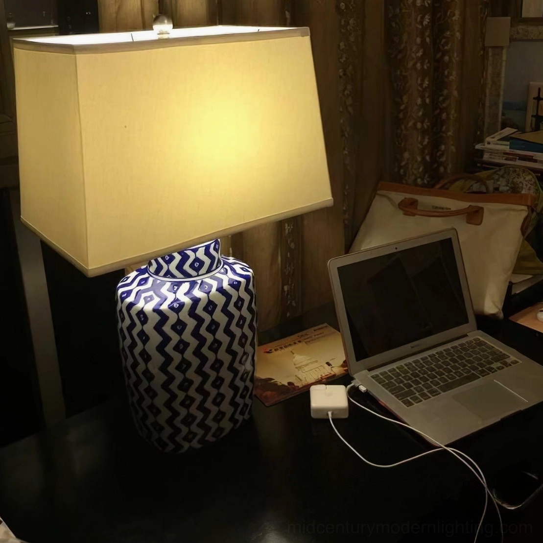 Beryl table lamp illuminated in home office workspace, showing warm light from white fabric shade with geometric ceramic base