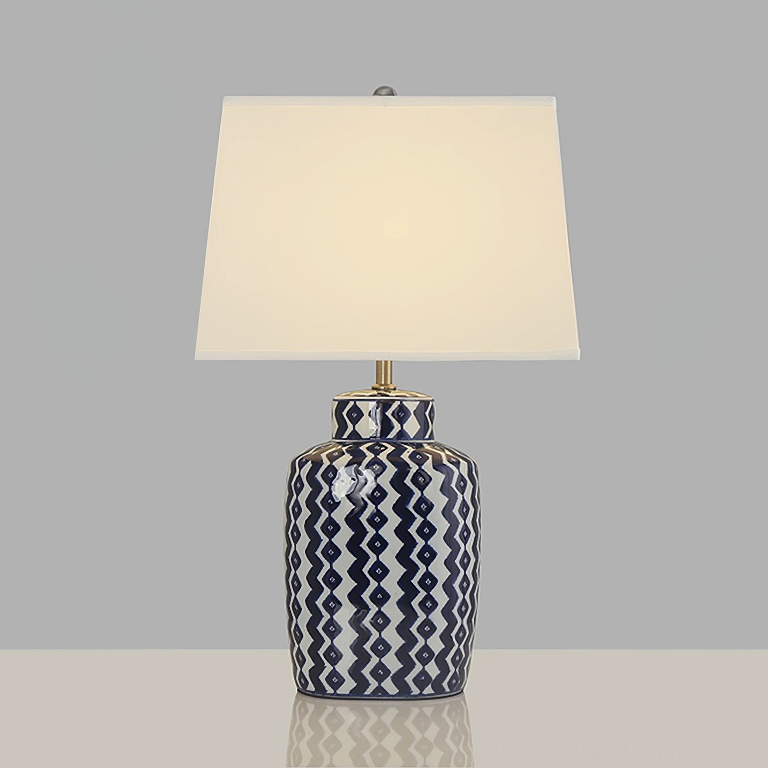 Beryl mid-century modern table lamp with polished metal accents and geometric patterned ceramic base on grey studio surface