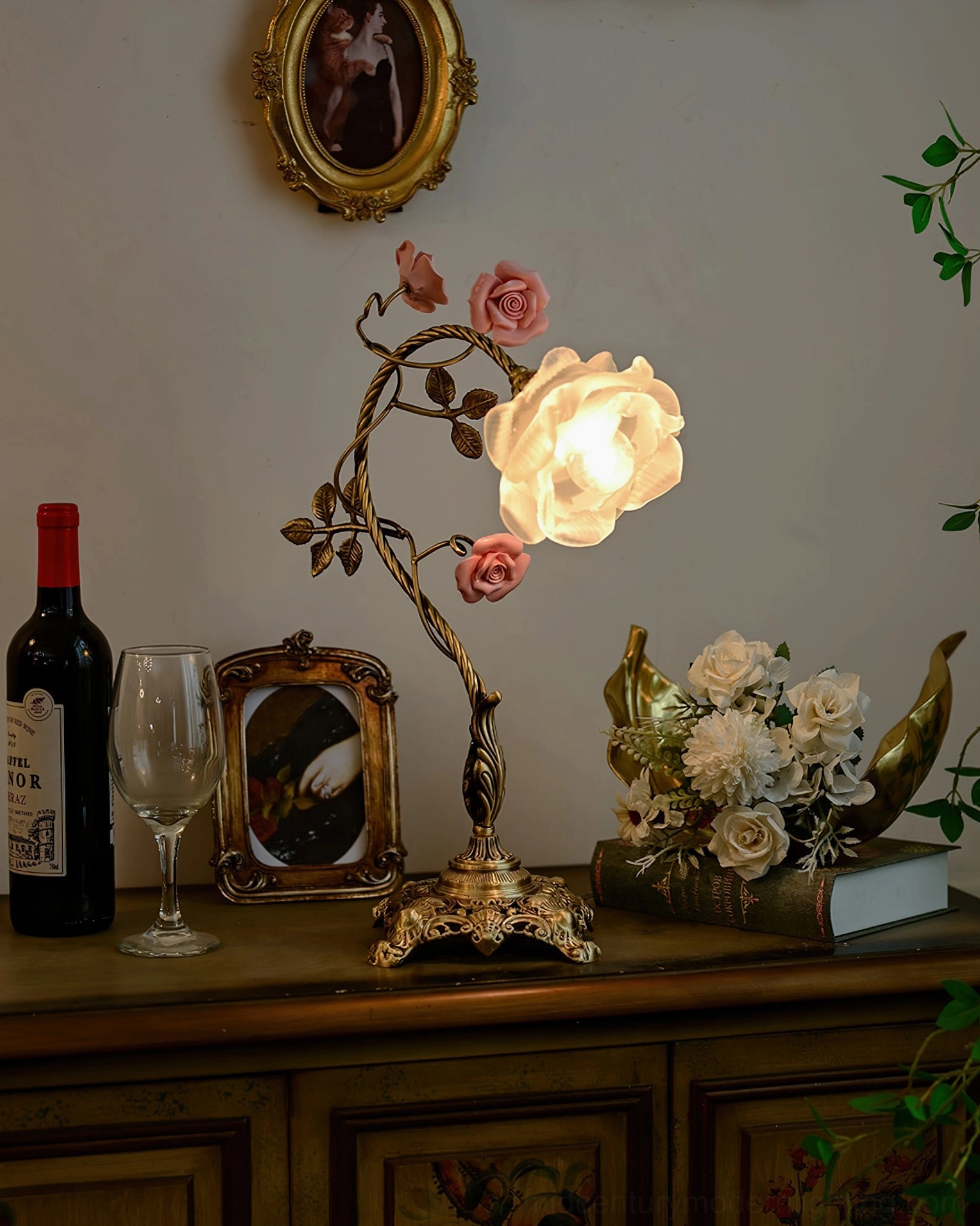 Illuminated Beulah botanical lamp on vintage dresser with framed portrait and elegant tabletop styling