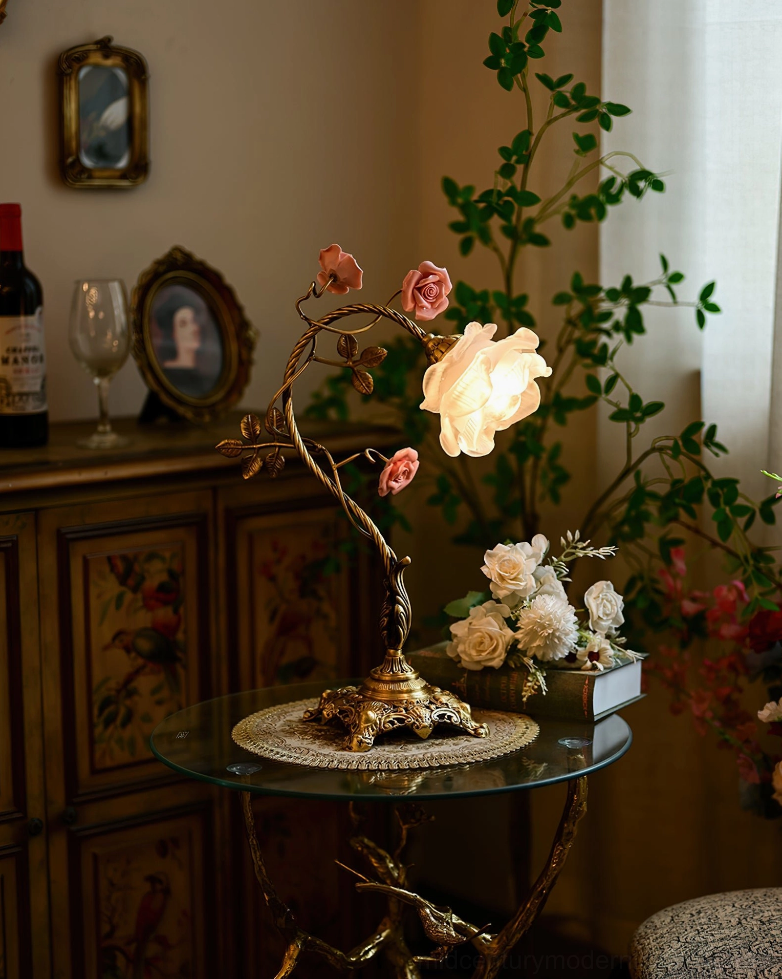 Low-angle view of lit Beulah rose table lamp with carved wooden cabinet and vintage interior details