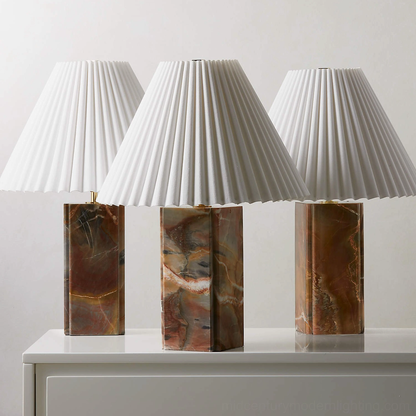 Set of three Bianca marble table lamps with varied veined marble bases on display dresser