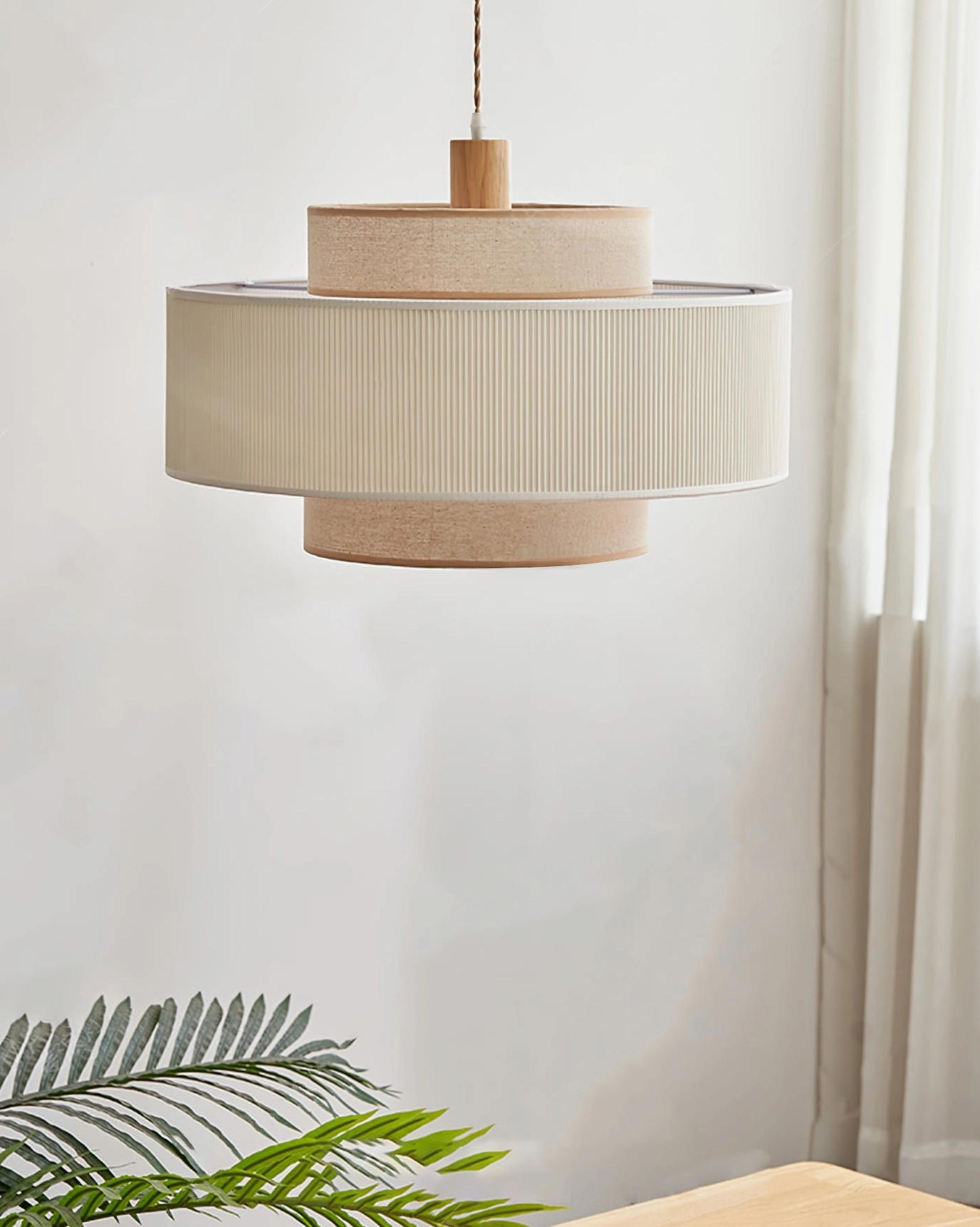 Side view of Bianella two-tier fabric pendant lamp in dining area with foliage, neutral beige linen shade