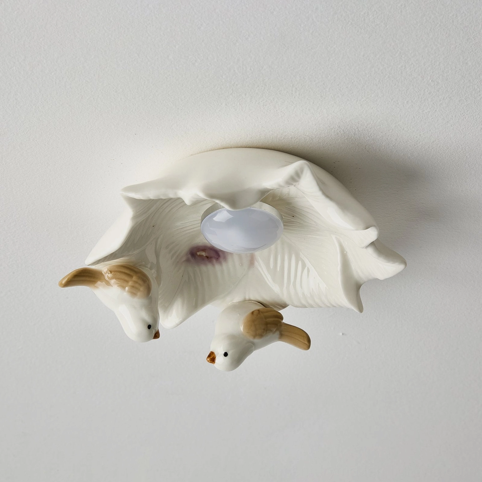 Bilal Bird ceiling fixture from below showing off-white ceramic birds perched on flower-shaped light diffuser base