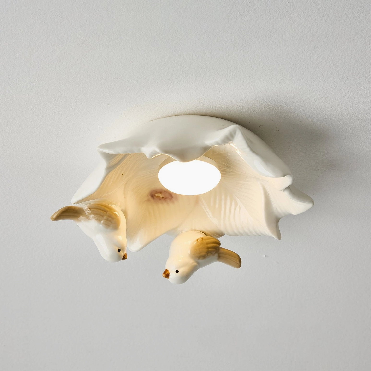 Illuminated Bilal Bird LED ceiling light glowing softly demonstrating warm ambient light quality and bird silhouettes