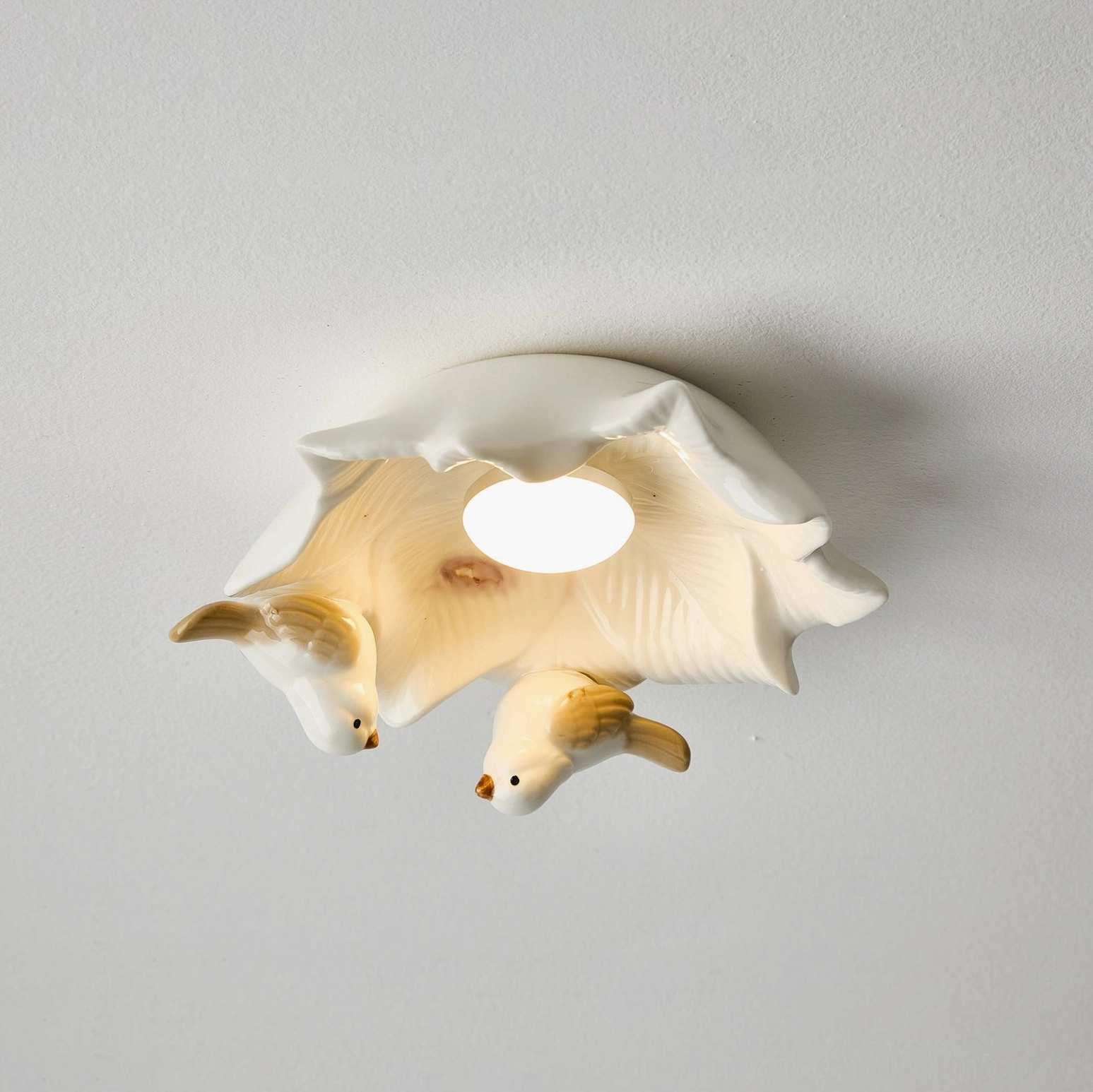 Bilal Bird ceramic ceiling light lit from below displaying soft light diffusion through sculptural bird design