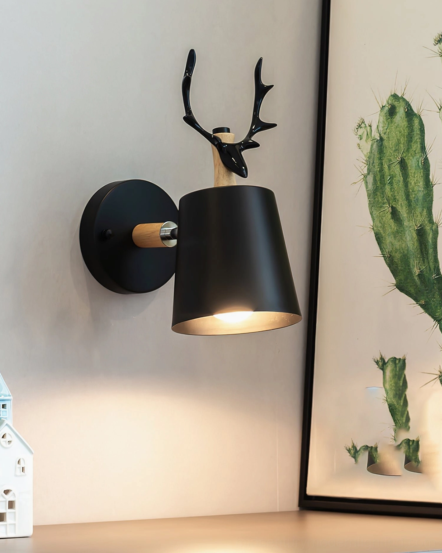 Black matte antler wall lamp mounted on gray wall with modern interior decor, side view showing warm ambient light