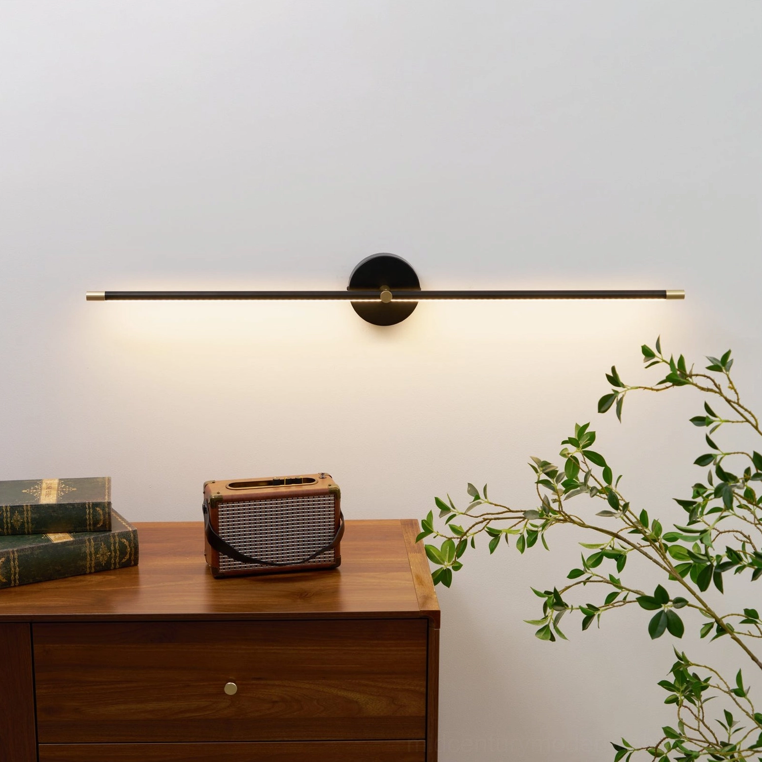 Sleek black linear wall lamp above wooden console table with vintage radio and books