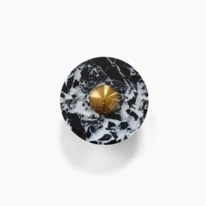 Overhead view of black marble and brass geometric wall lamp showing circular disc design with white veining detail against white background