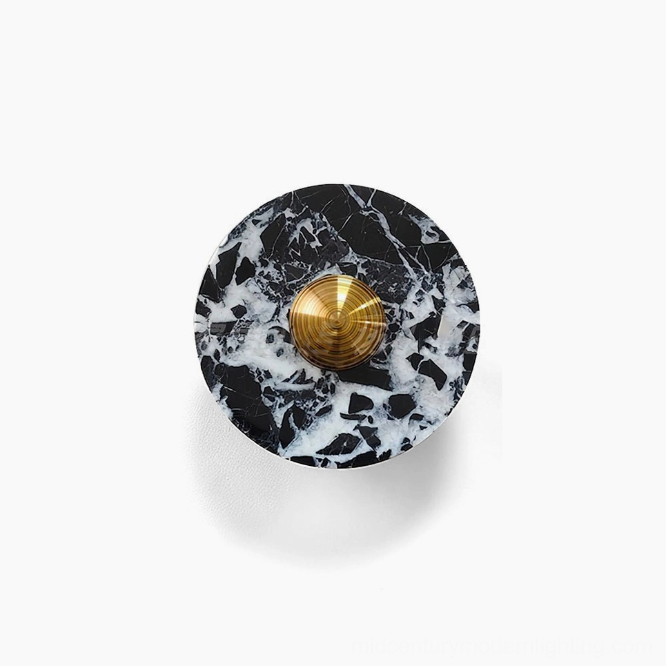 Overhead view of black marble and brass geometric wall lamp showing circular disc design with white veining detail against white background