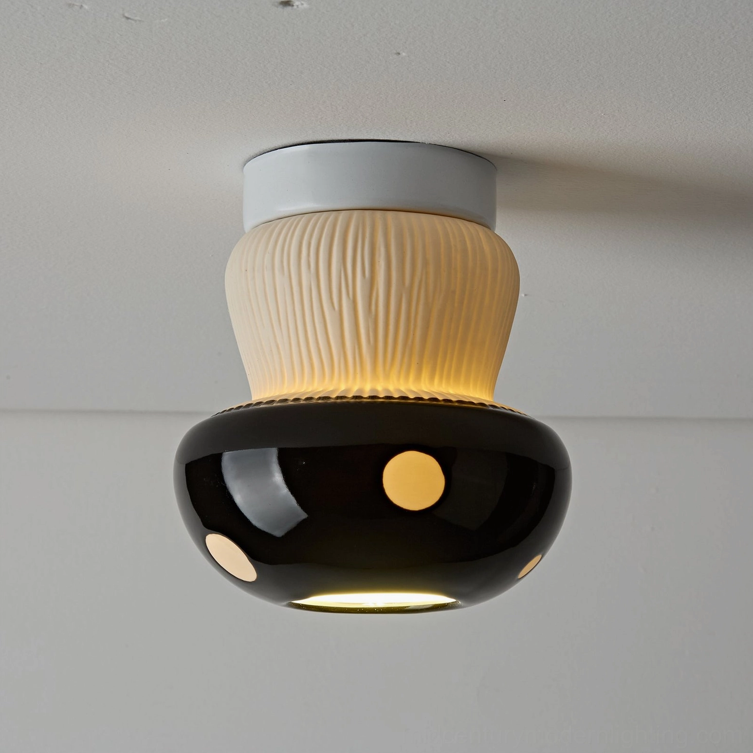 Black mushroom flush mount light on white ceiling showing warm downlight glow effect