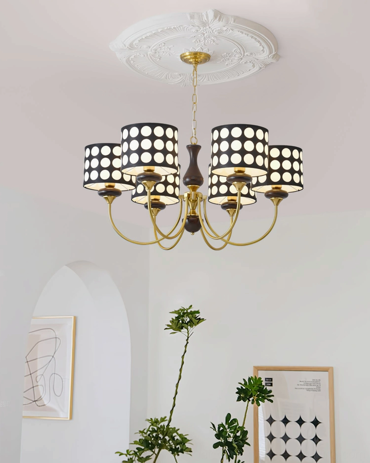 Black polka dot chandelier installed in Nordic minimalist home with wall art and green plants, low angle perspective