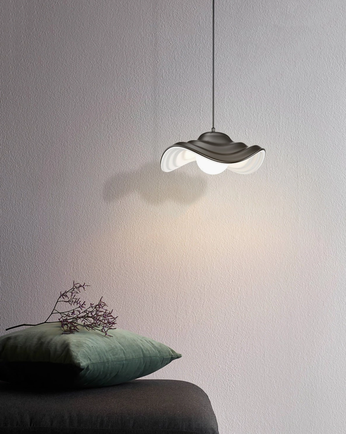 Matte black wavy pendant light installed as side accent lighting in modern lounge corner, demonstrating sculptural design and contemporary aesthetic
