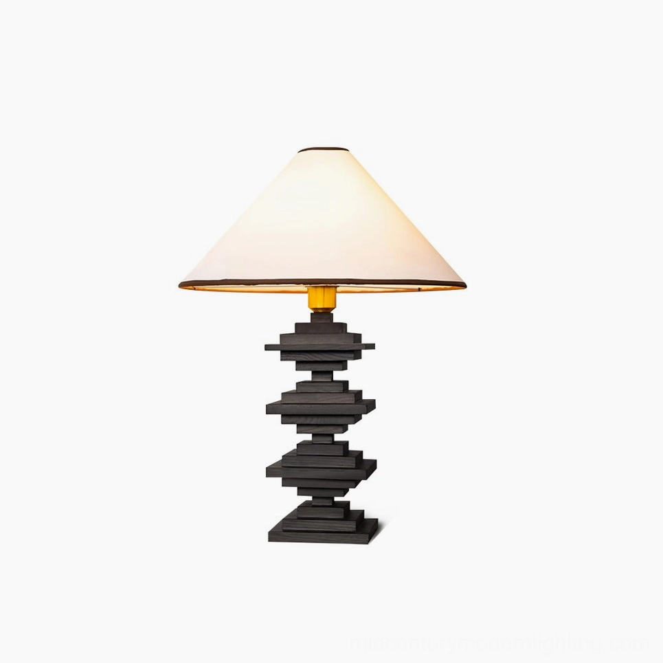 Black stacked wood tower table lamp with cream fabric shade and gold trim, architectural detail shot