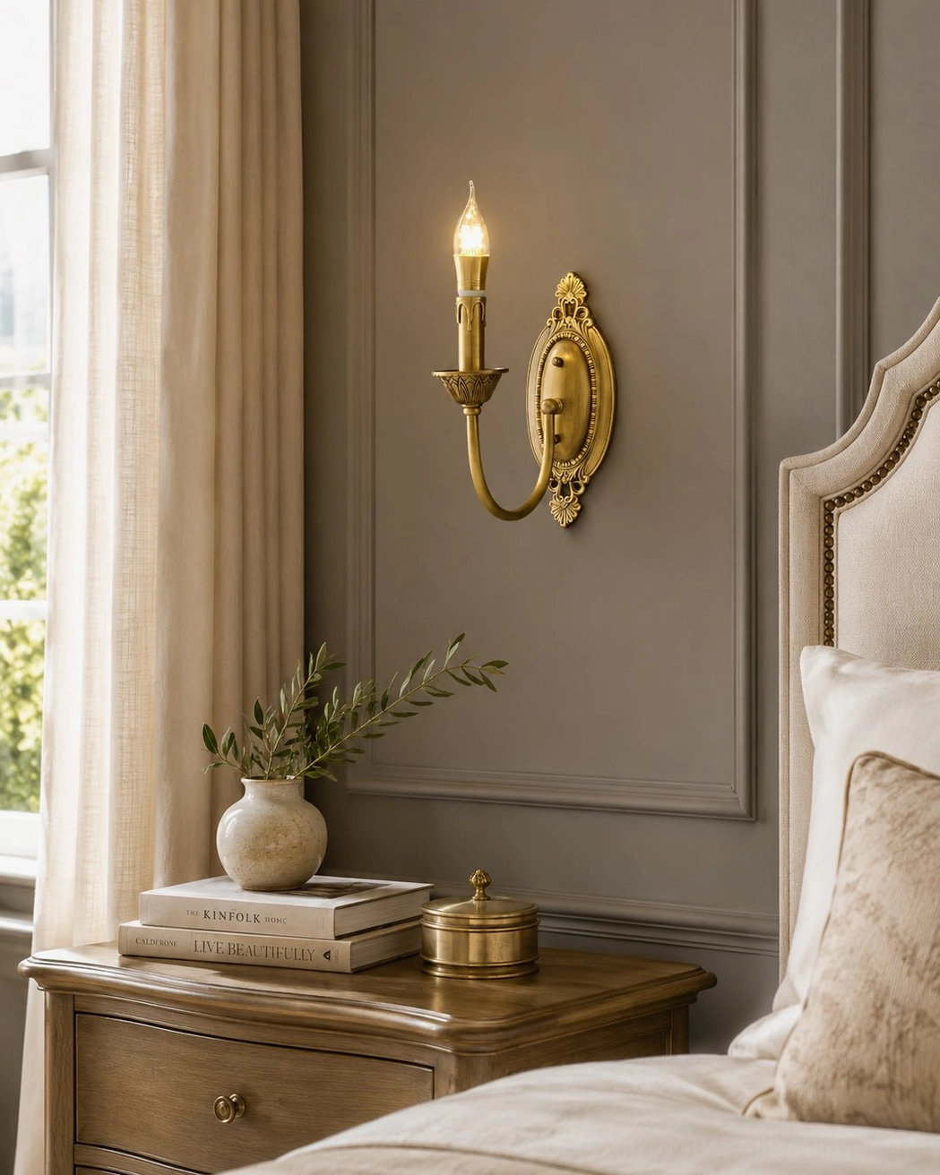 Single Blair brass candle sconce mounted on bedroom wall beside nightstand showing warm gold finish detail