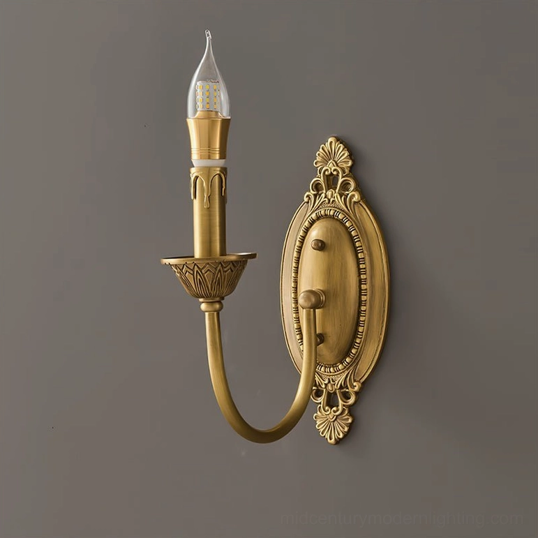 Blair brass candle wall sconce mounted on neutral bedroom wall showing warm brass finish and sculptural form