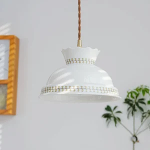 Mid-century modern pendant lamp overhead view showing scalloped rim ceramic shade hanging in home interior with wall art and green plant decor