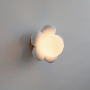 Bloom wall lamp side profile showing frosted glass petals and warm glowing light against gray wall