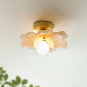 Blossom ceiling lamp champagne finish glowing with lit globe bulb in modern interior with green leaf decor
