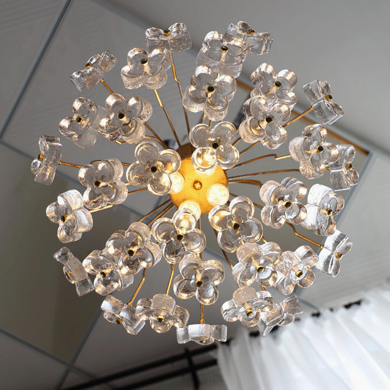 Bottom-up view of lit Blossom pendant light revealing internal LED bulb structure against industrial ceiling
