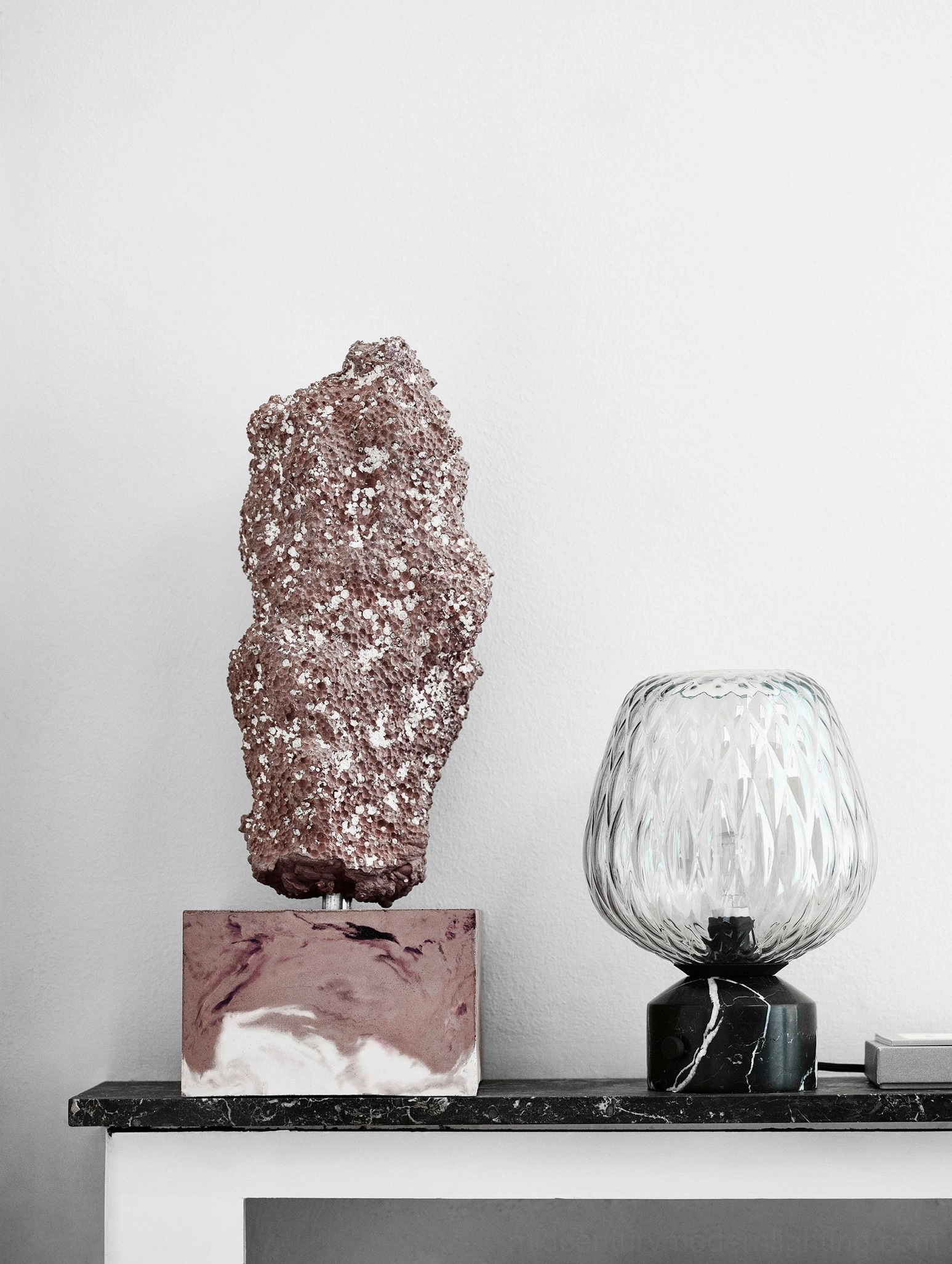 Hand-blown textured glass lamp on fireplace mantel paired with mineral décor, luxury minimalist design