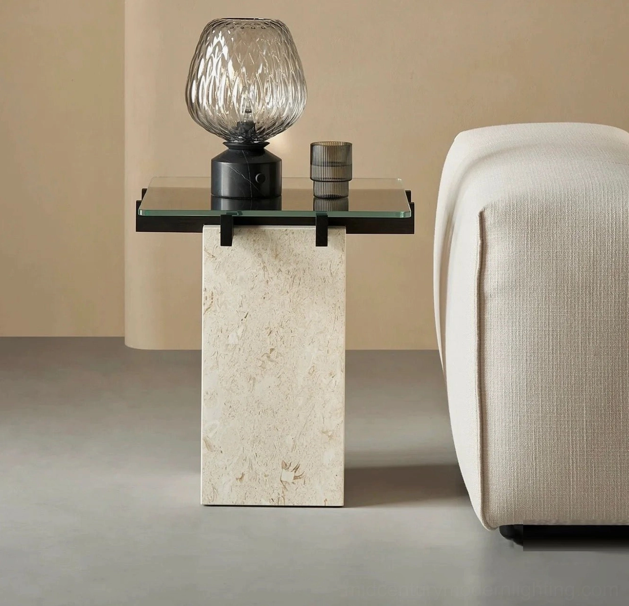 Blown glass lamp on travertine side table in contemporary living room, beside beige fabric sofa