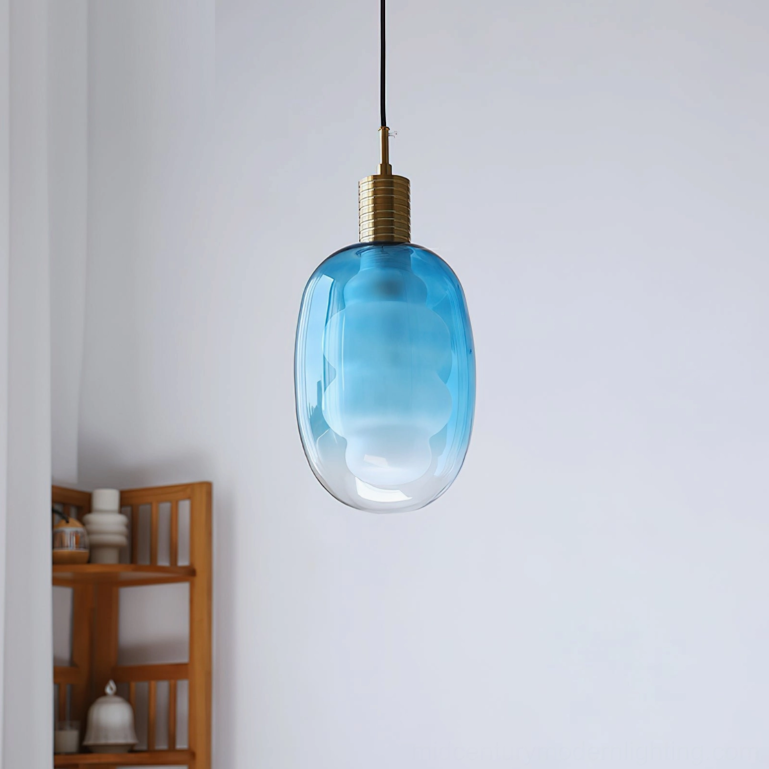 Blue gradient sculptural pendant light in minimalist interior, brass fixture detail, warm glow