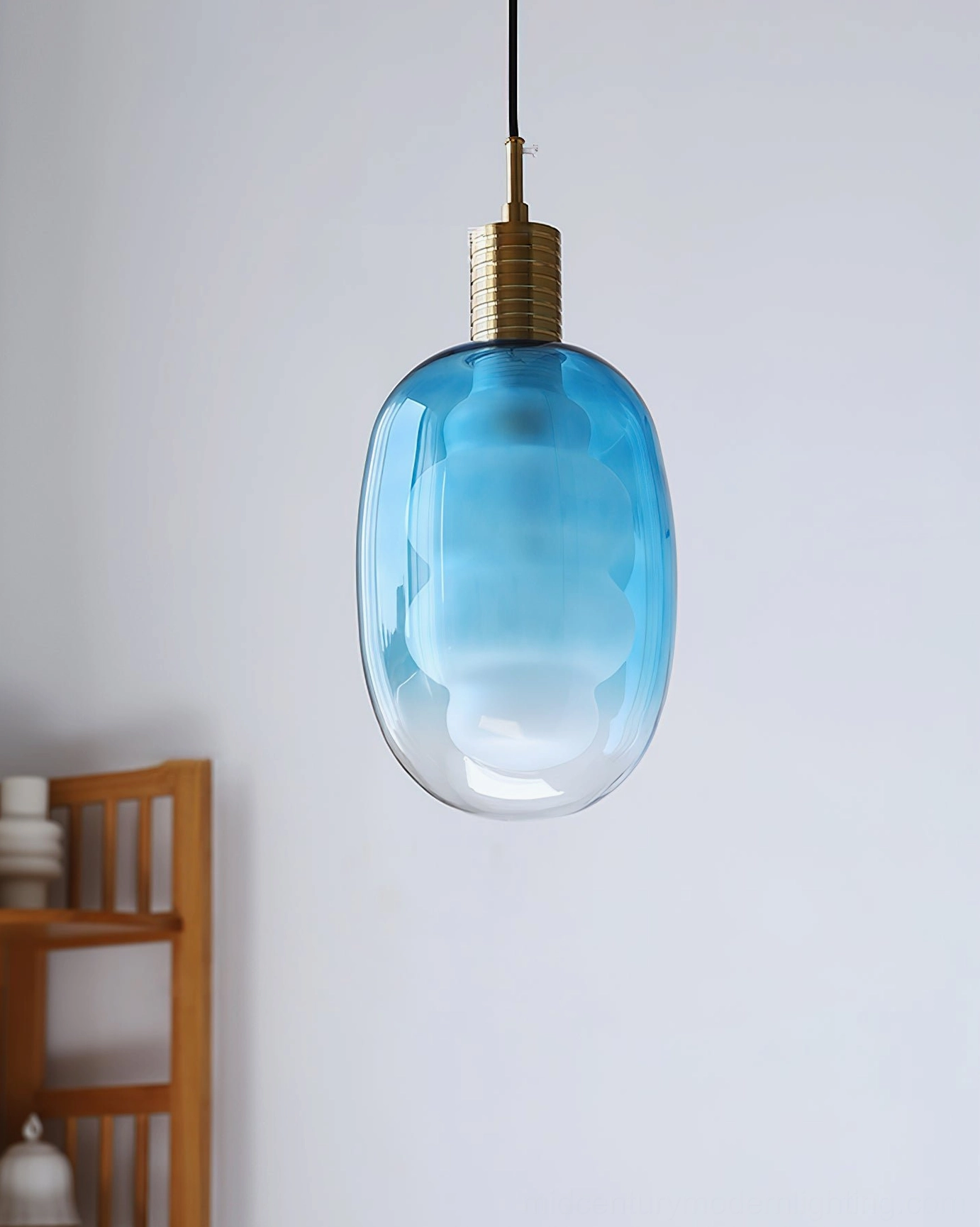 Gradient blue sculptural pendant light with brass top, minimalist home setting, ambient illumination