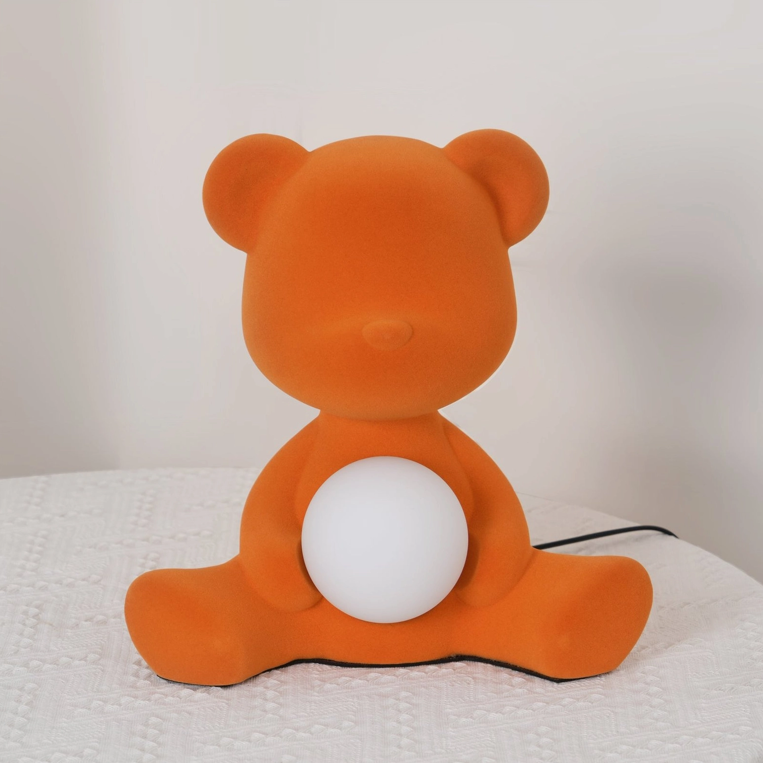 Blue teddy bear table lamp glowing on flat surface with warm ambient light