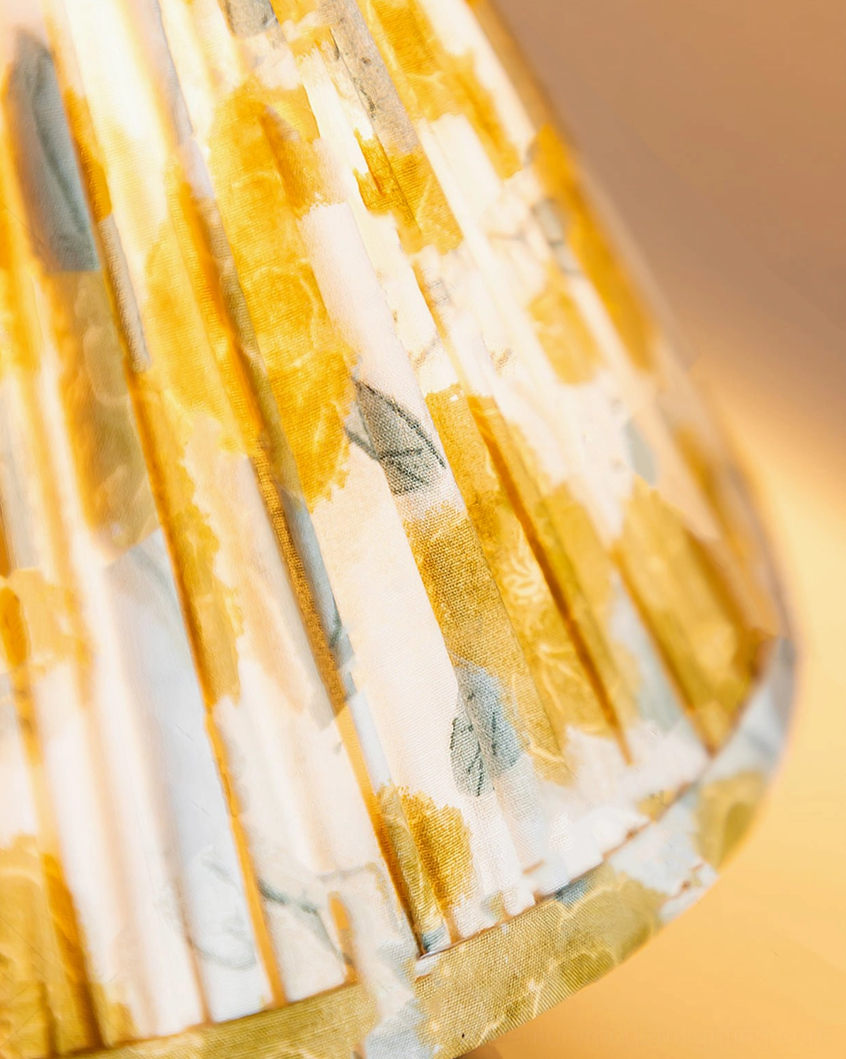 Detailed view of pleated yellow fabric shade on Bobbin mid-century modern table lamp with warm glow