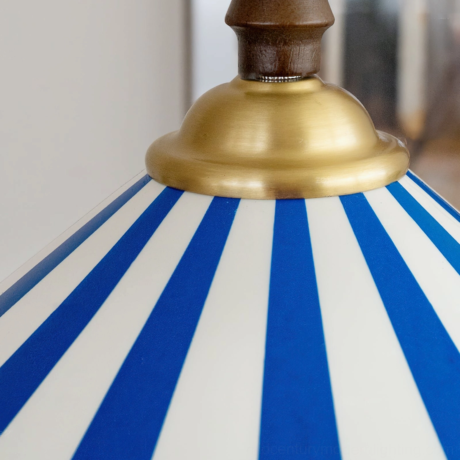 Close-up detail of Bobine pendant light showing brass metal collar, blue-white striped ceramic texture, wood mount