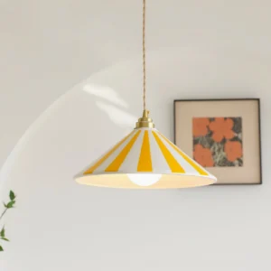 Yellow and white striped Bobine pendant light hanging at eye level in minimalist interior with floral artwork