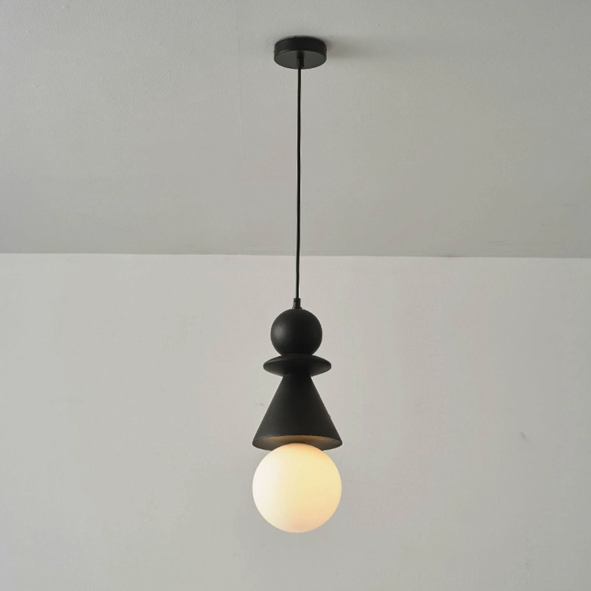 Black stacked geometric totem pendant light mounted on ceiling with illuminated frosted globe, warm ambiance overhead perspective