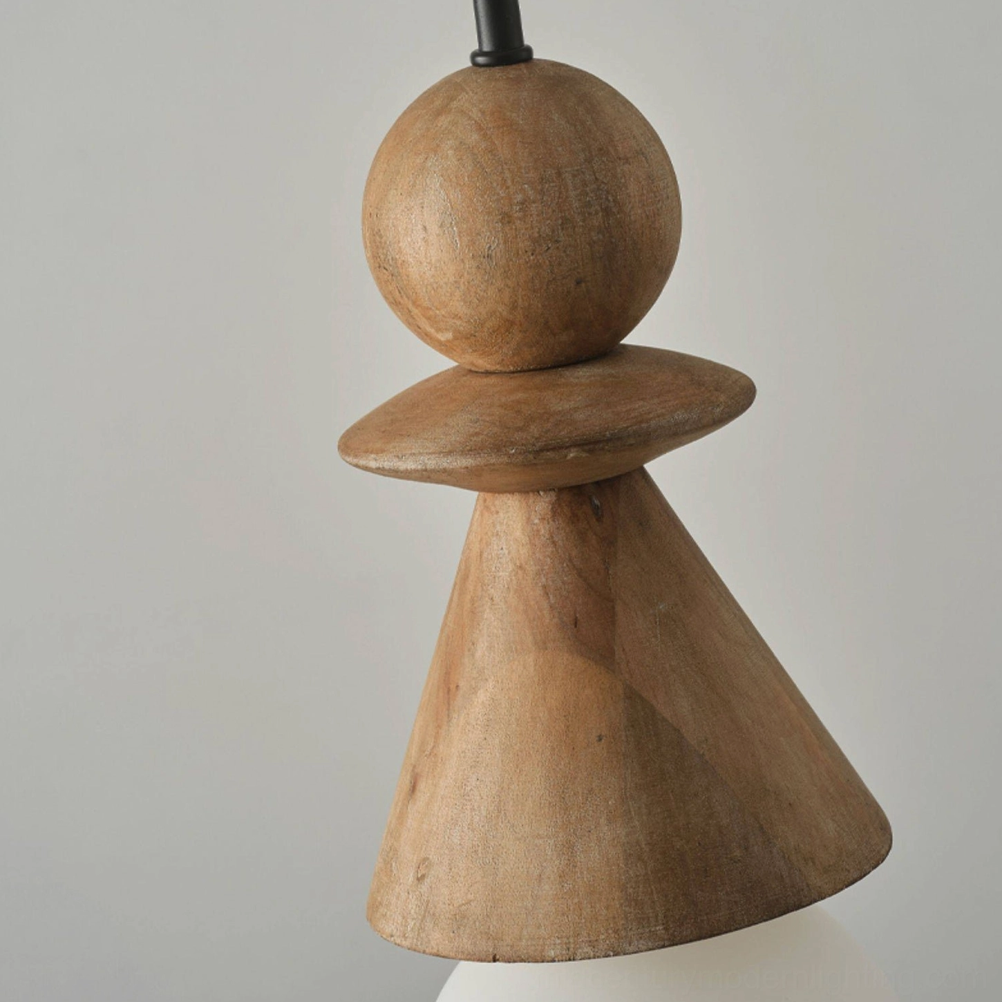 Low-angle close-up detail of Bodie wood totem pendant showing stacked spheres and conical forms with visible wood grain on white background