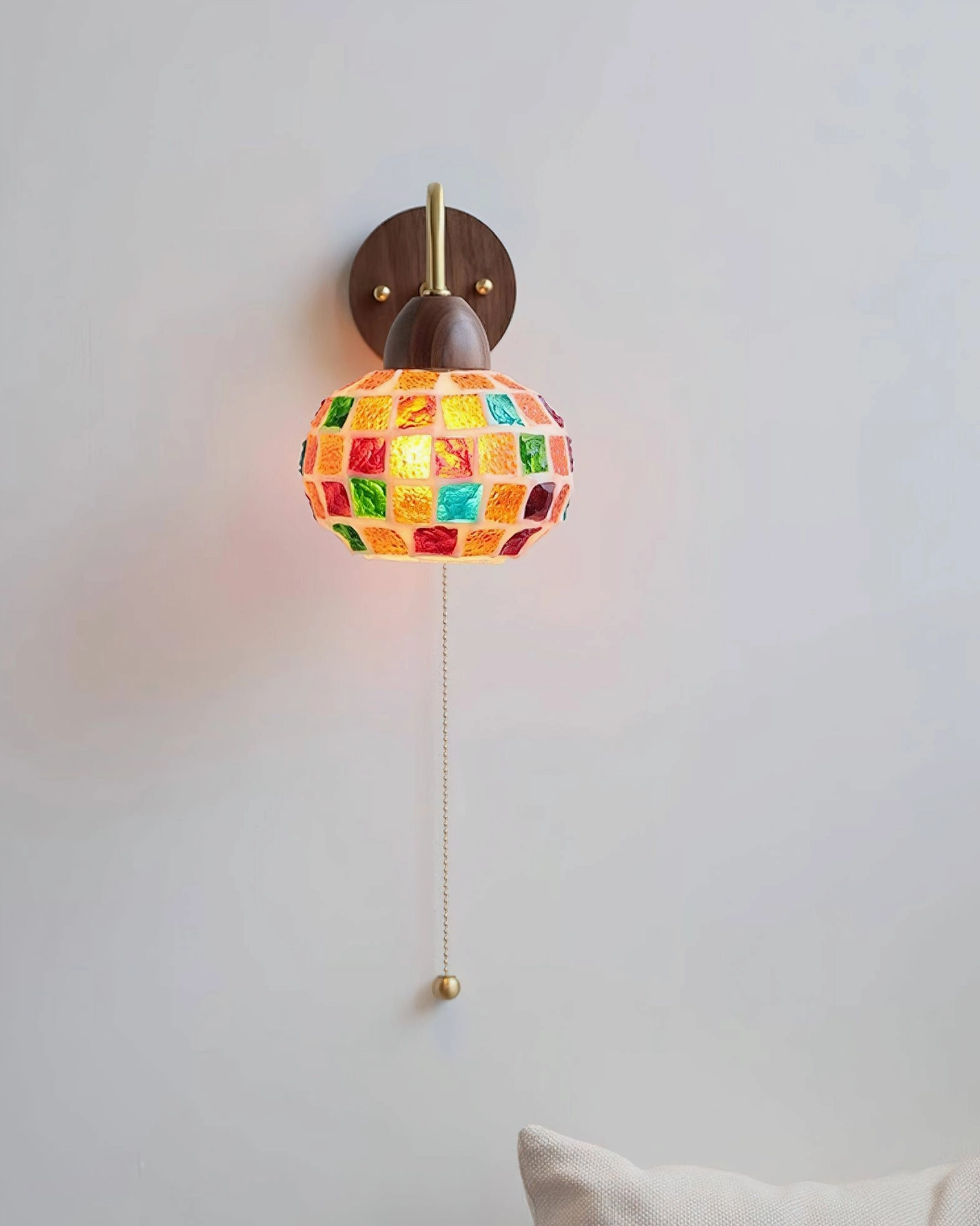 Bohemian mosaic wall lamp with artistic glass shade casting colorful light patterns on interior wall space