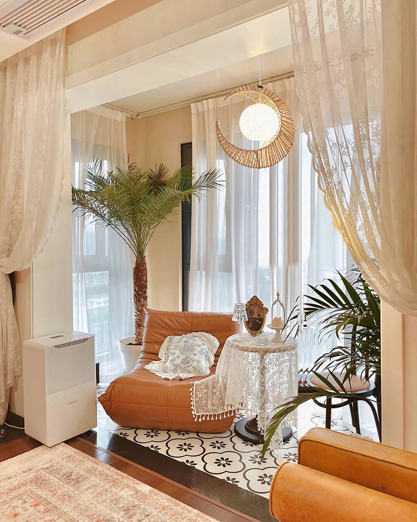 Bohemian moon lamp hanging in cozy living lounge with green plants, sheer curtains and natural bohemian style