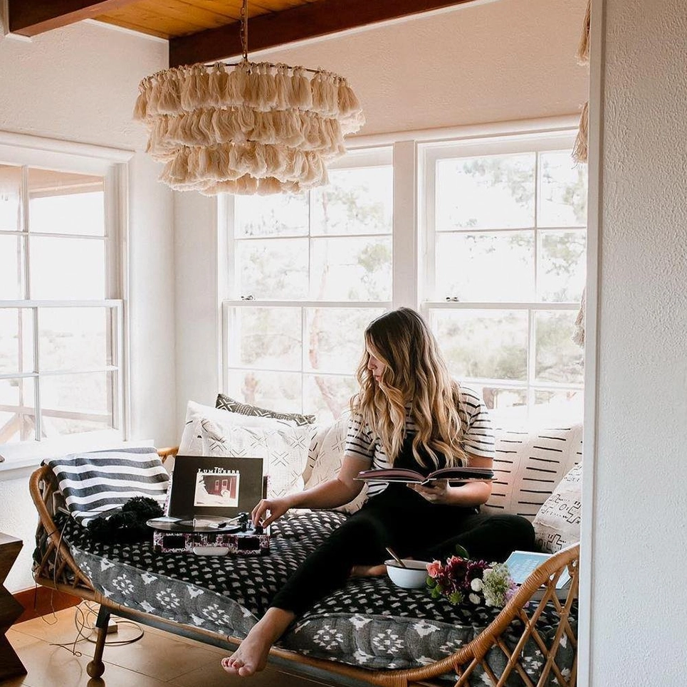 Eclectic tassel chandelier lighting cozy bohemian work-from-home lounge with natural sunlight