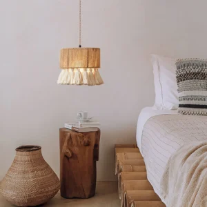Bohemian tassel pendant light hanging in minimalist bedroom, warm ambient lighting through woven hemp shade