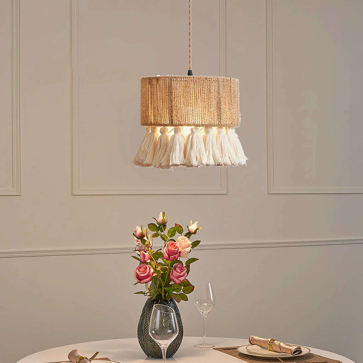 Boho tassel pendant lamp above elegant dining table setting with flowers and tableware, eye-level indoor view