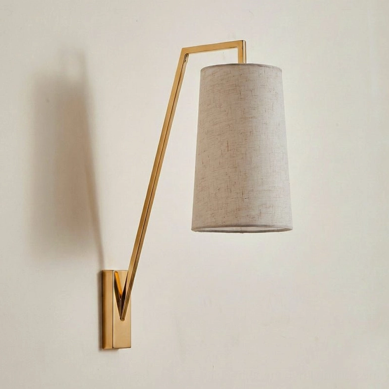 Brass finish Bonny wall light with tapered beige linen lampshade in modern minimalist style, front view on off-white wall
