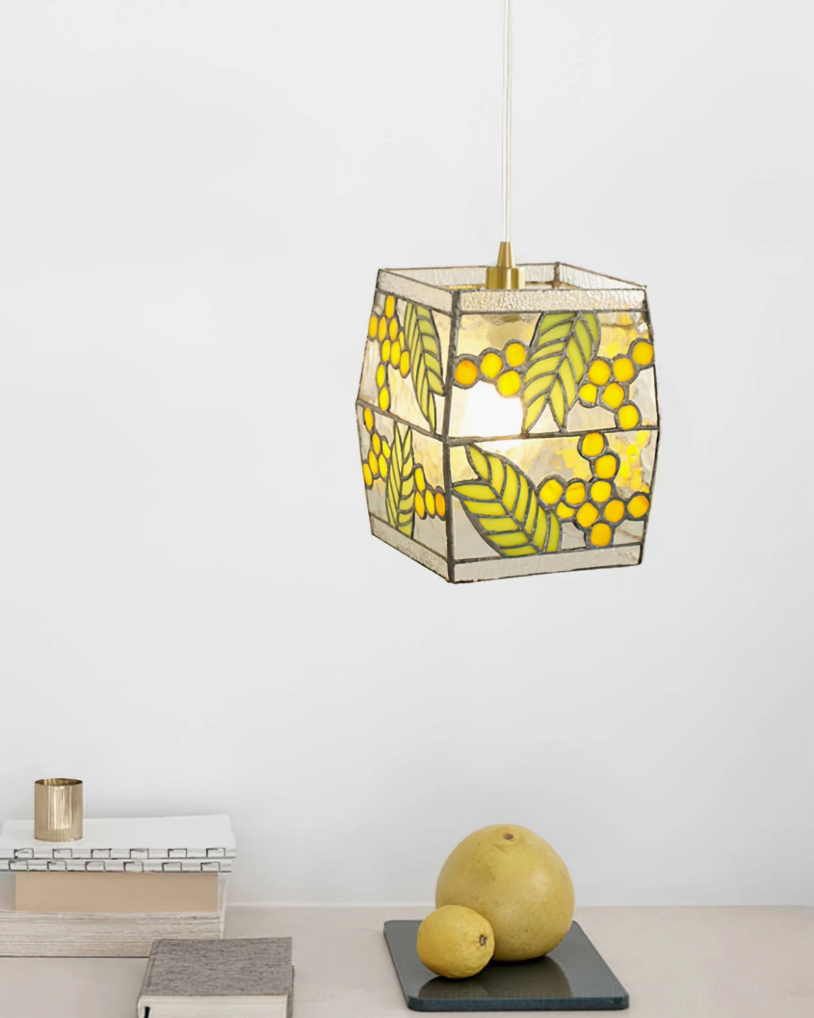 Front-hanging view of botanical stained glass pendant lamp in minimalist interior with fruit decor, warm illumination