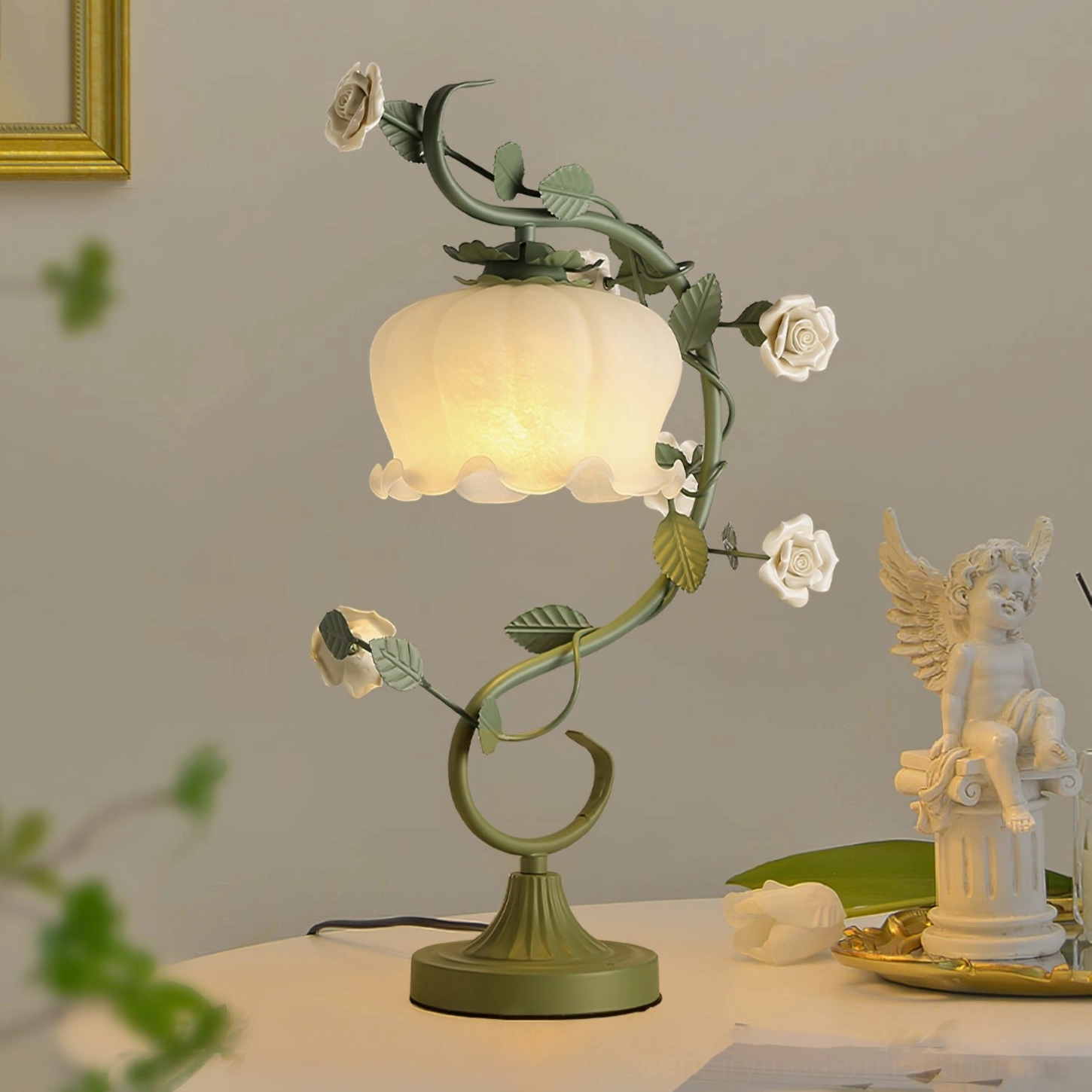 Sage green rose vine table lamp three-quarter view with angel figurine and vintage tabletop styling