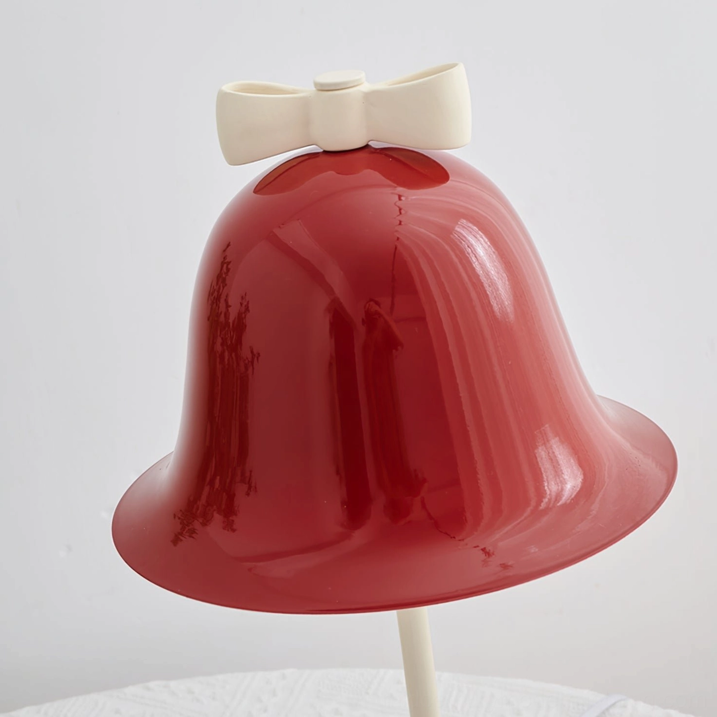 Bow Bell red table lamp ambient lighting effect in room setting, warm glow through burgundy shade creating cozy atmosphere