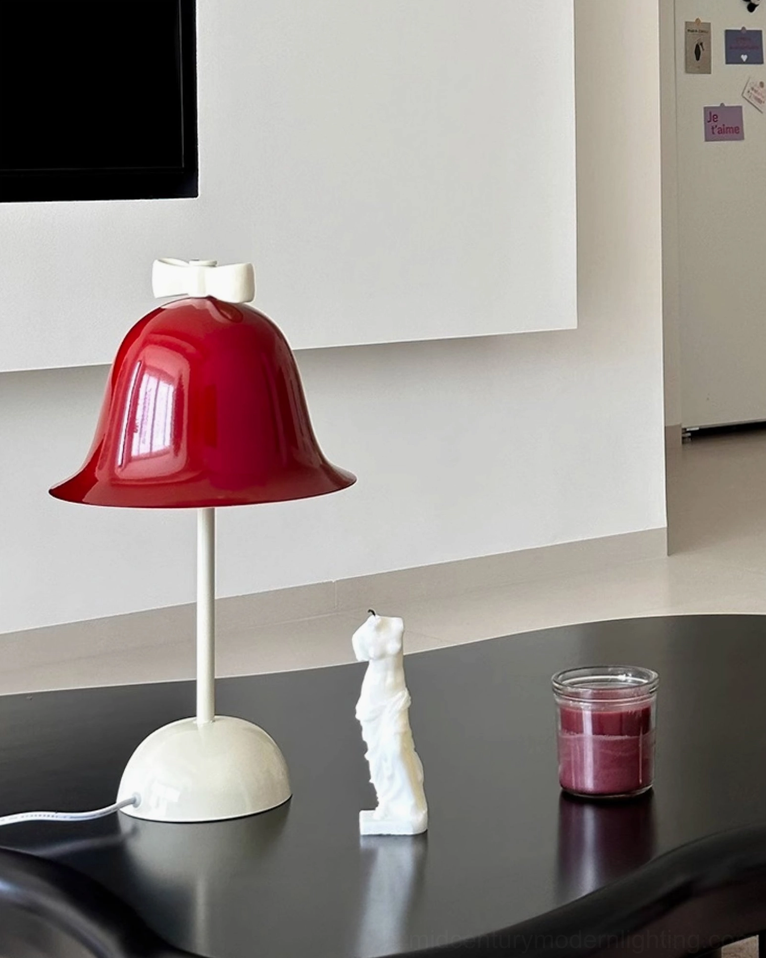 Red burgundy Bow Bell lamp on black modern accent table with white cat figurine and scented candle home décor
