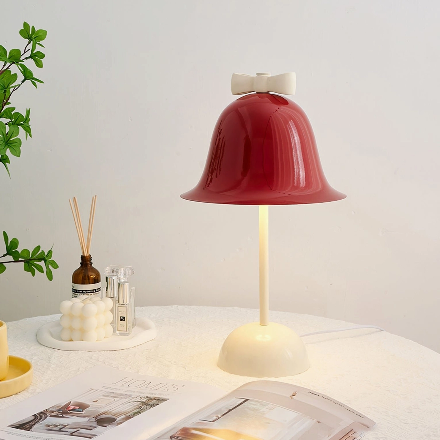 Mid-century modern Bow Bell lamp with green plant decor, reed diffuser, candle, and home magazines on contemporary table
