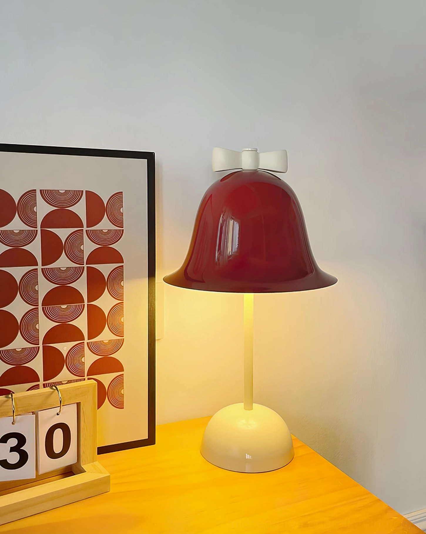 Bow Bell table lamp illuminated view showing warm light diffusion through burgundy shade and cozy room ambiance